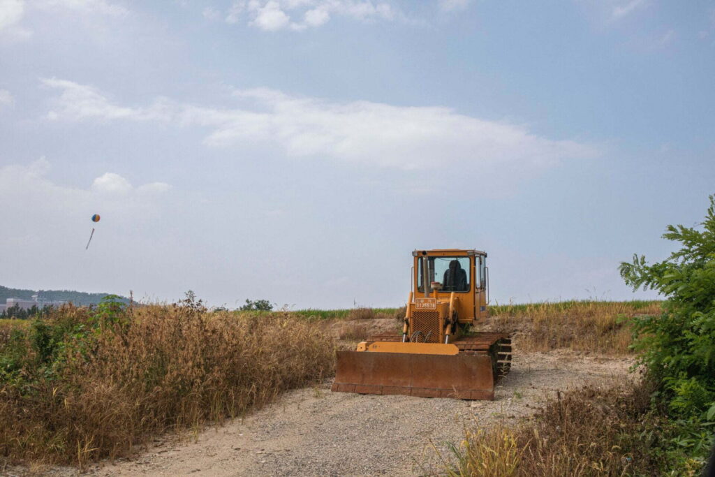 yellow and black heavy equipment on brown field under white clouds during daytime
