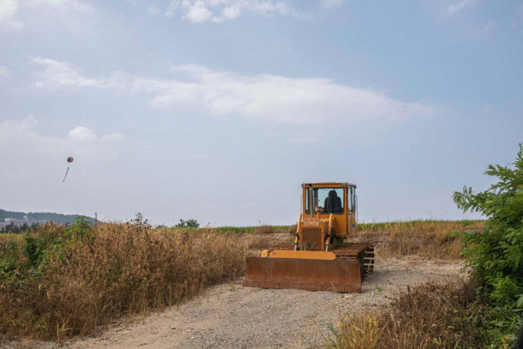 yellow and black heavy equipment on brown field under white clouds during daytime