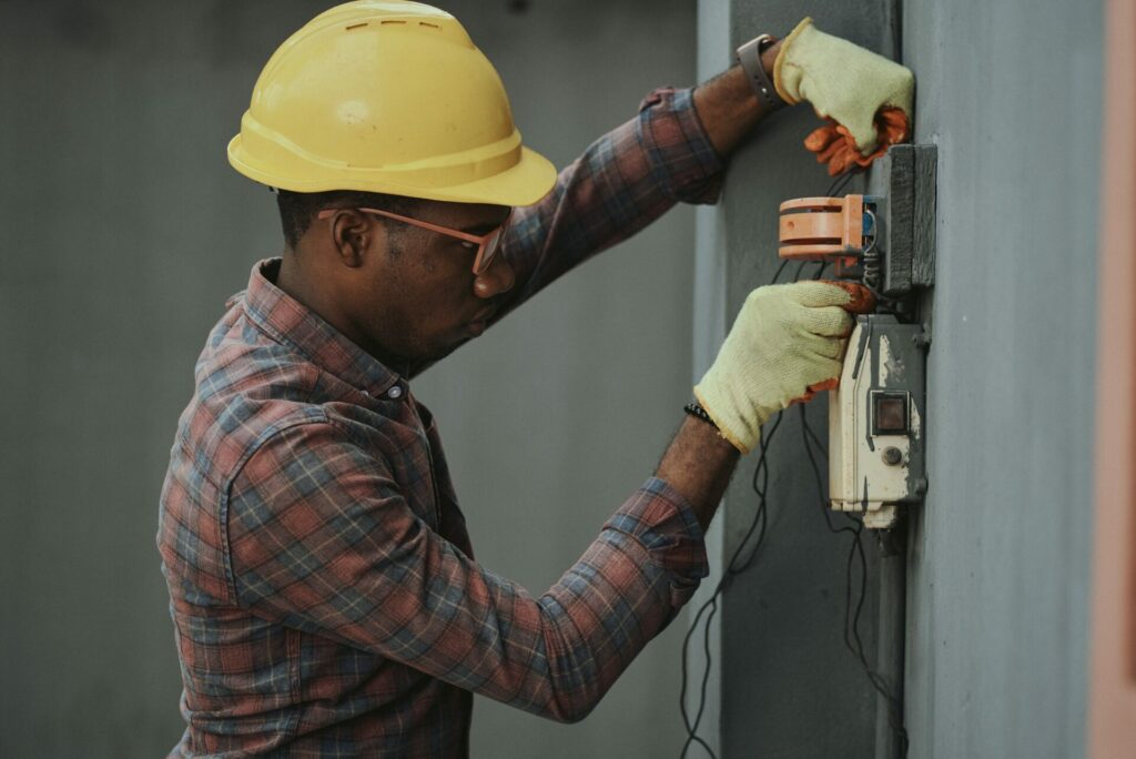 Portrait of a black man architect at a building site looking at camera. Confident civil engineering wearing a hardhat and eye goggles. Successful mature civil engineer at a construction site with open