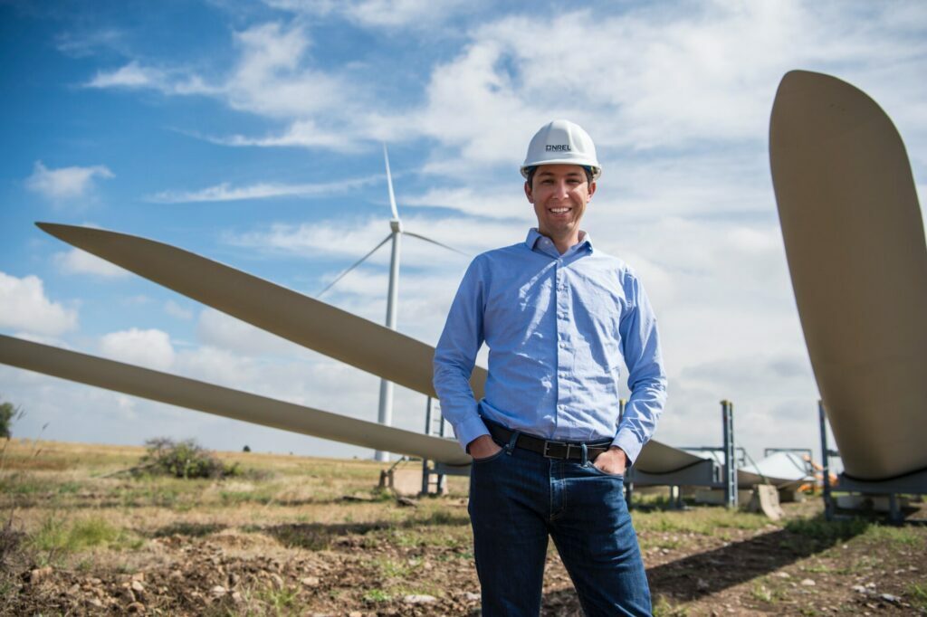 man smiling and standing near windmill